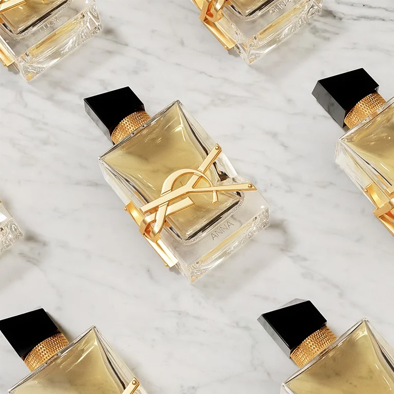 Flacons de parfum YSL Libre personnalisés avec des gravures de prénoms, disposés sur un marbre blanc.