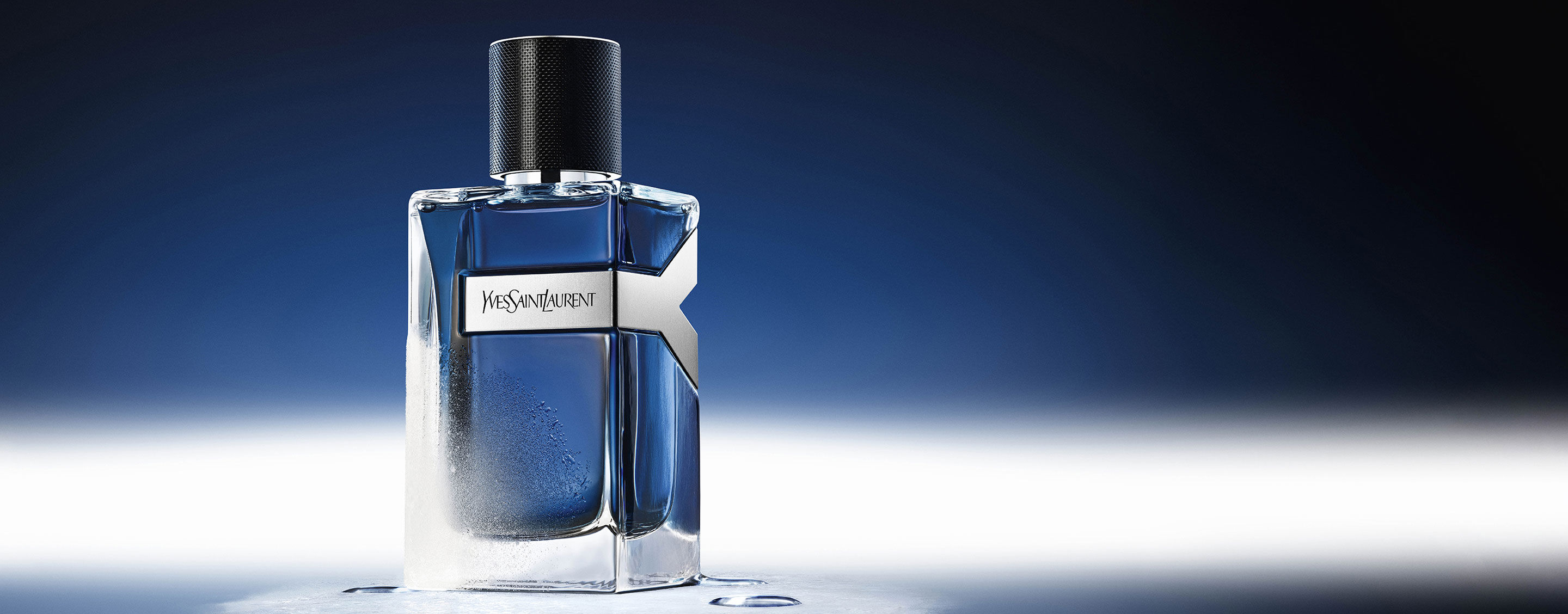 Flacon de 100 ml de YSL Y Eau de Toilette Intense Iced Cologne, givré et couvert de gouttelettes d'eau, reflétant une ambiance bleu glacier.