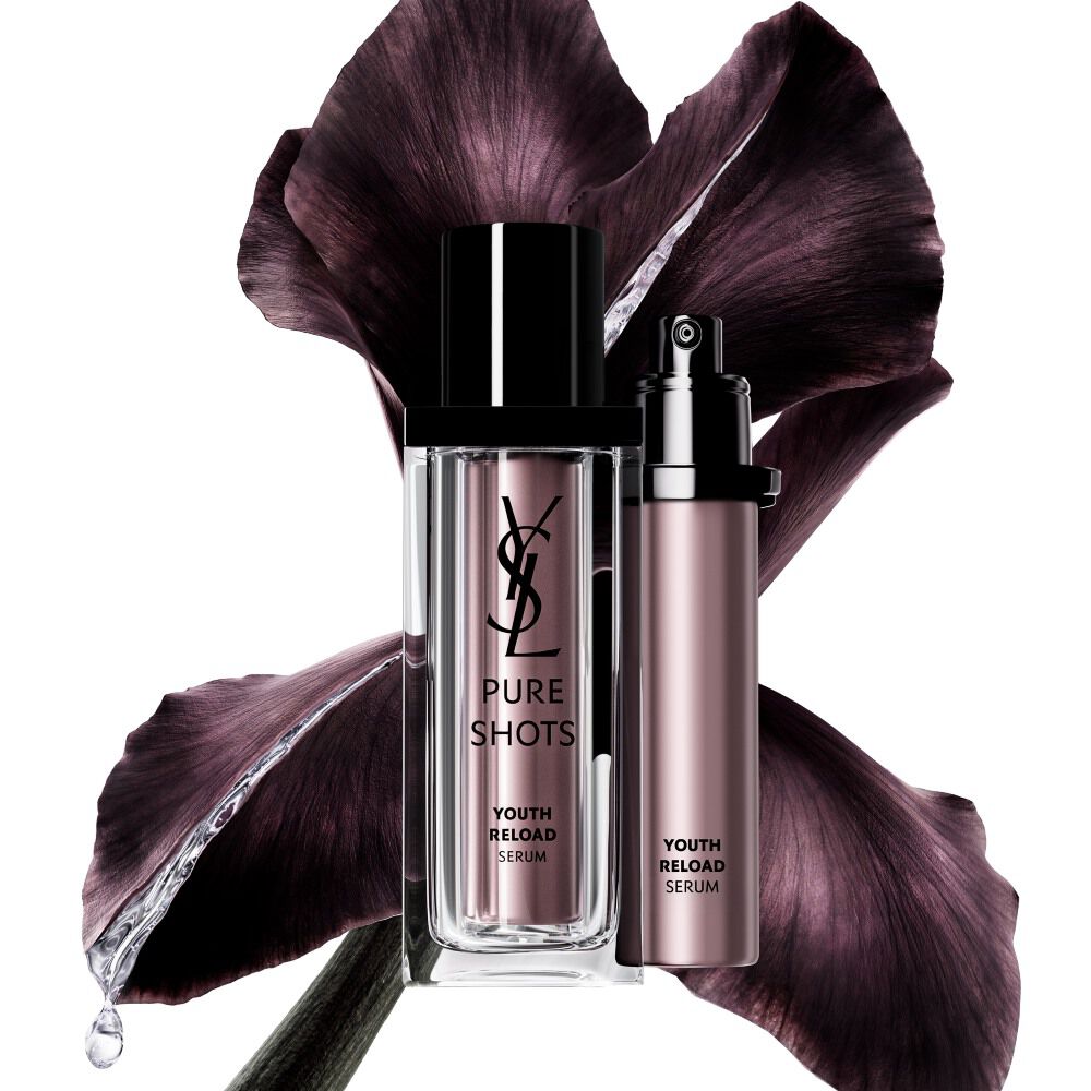 Flacon du Pure Shots Youth Reload Serum et sa recharge durable de YSL Beauty, placé devant une fleur d’iris violette foncée.