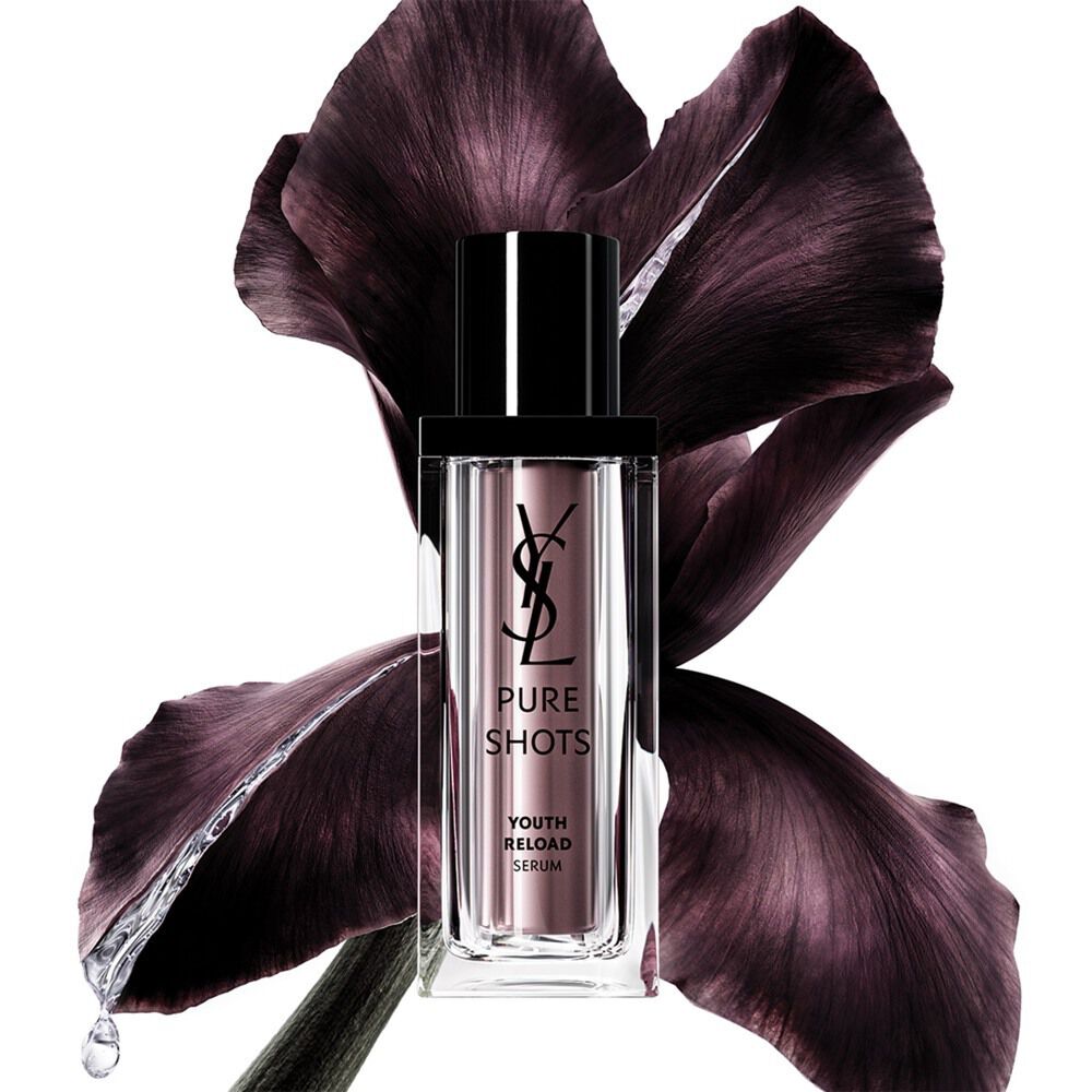 Flacon du Pure Shots Youth Reload Serum de YSL Beauty, élégamment positionné devant une fleur d'iris violette foncée.
