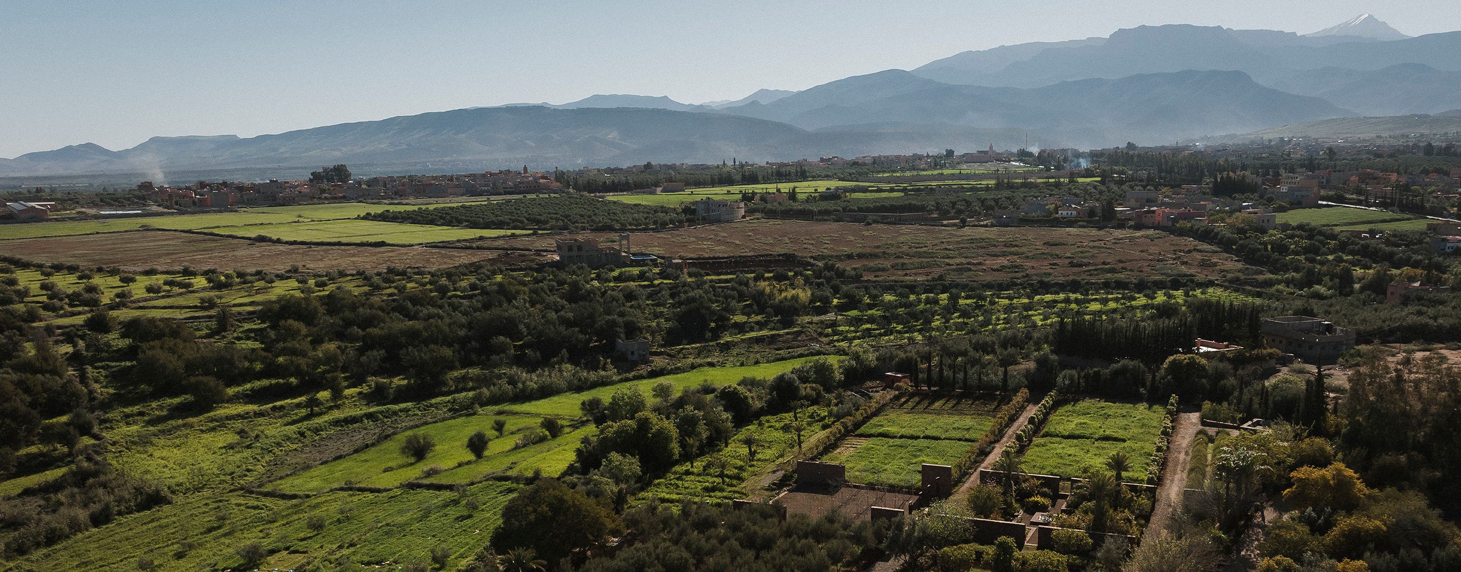 Les Jardins d’Ourika, avec des champs verdoyants et des montagnes au loin.