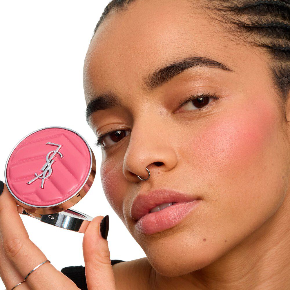 Gros plan d’un mannequin tenant le YSL Make Me Blush Lifted Glow Cream Blush, révélant un éclat lifté et radieux sur ses pommettes. Mieux