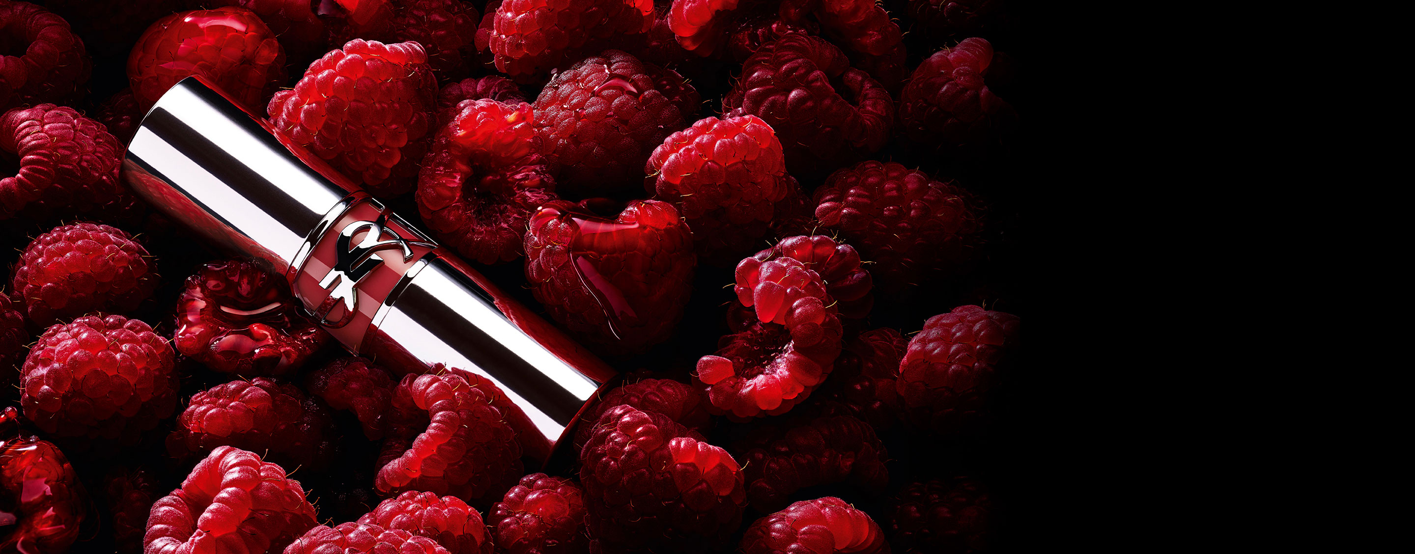 Rouge à lèvres YSL LOVESHINE Berry Crush, tube argenté orné du logo YSL couleur baie, niché parmi des framboises fraîches.