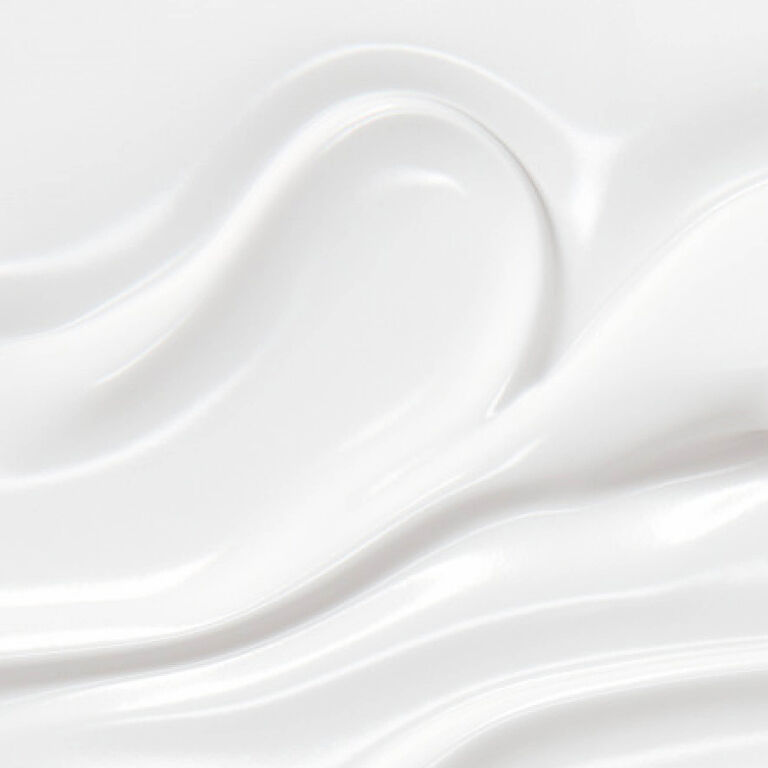 Un gros plan sur la texture blanche lisse et luxueuse de la crème Eye Reboot Pure Shots d'YSL, soulignant sa richesse.