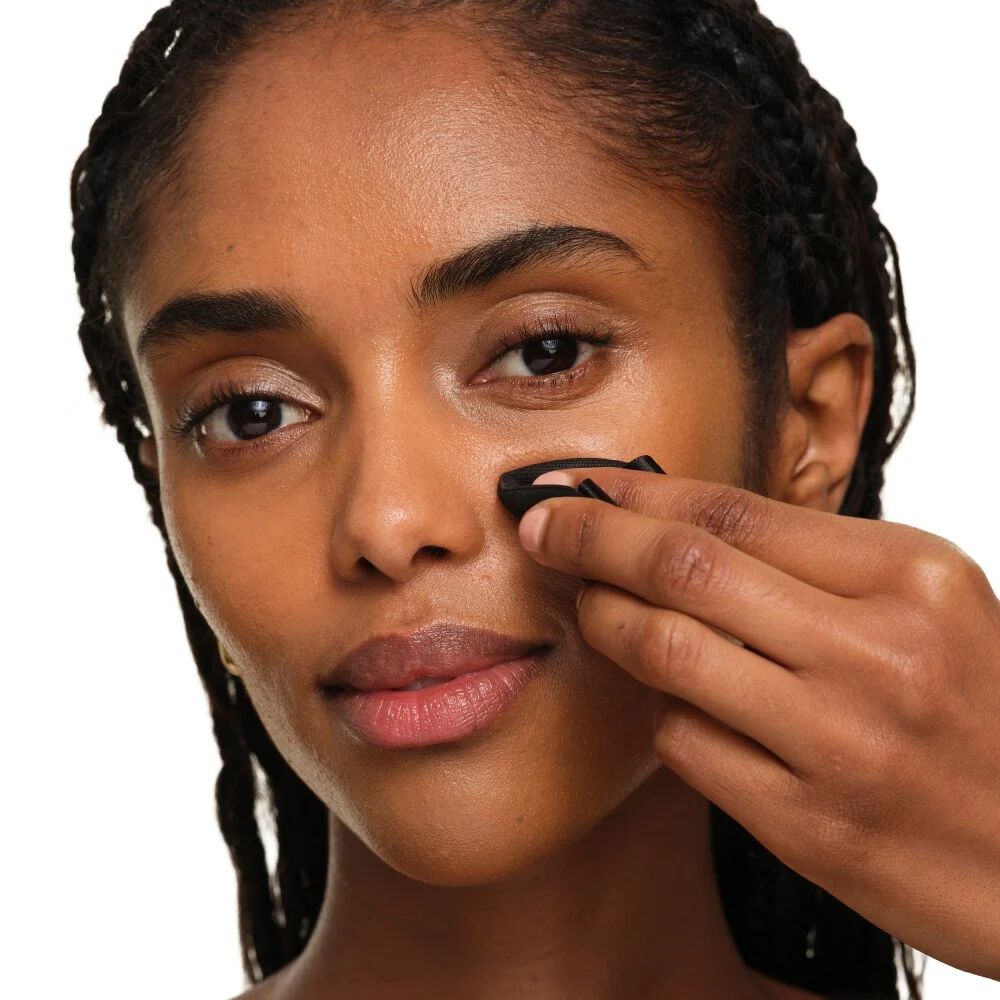Gros plan montrant comment plier la houppette YSL pour une précision ciblée et des retouches autour du nez et des yeux.