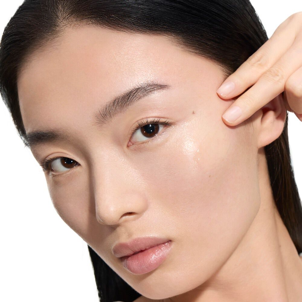 Wen, mannequin de YSL Beauty, à la peau claire, appliquant une goutte du Pure Shots Youth Reload Serum sur sa joue.