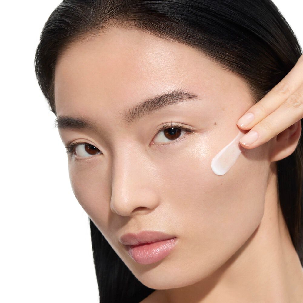 Wen, mannequin YSL Beauty, avec une peau claire, appliquant la crème YSL Beauty Pure Shots Youth Reload sur sa joue.