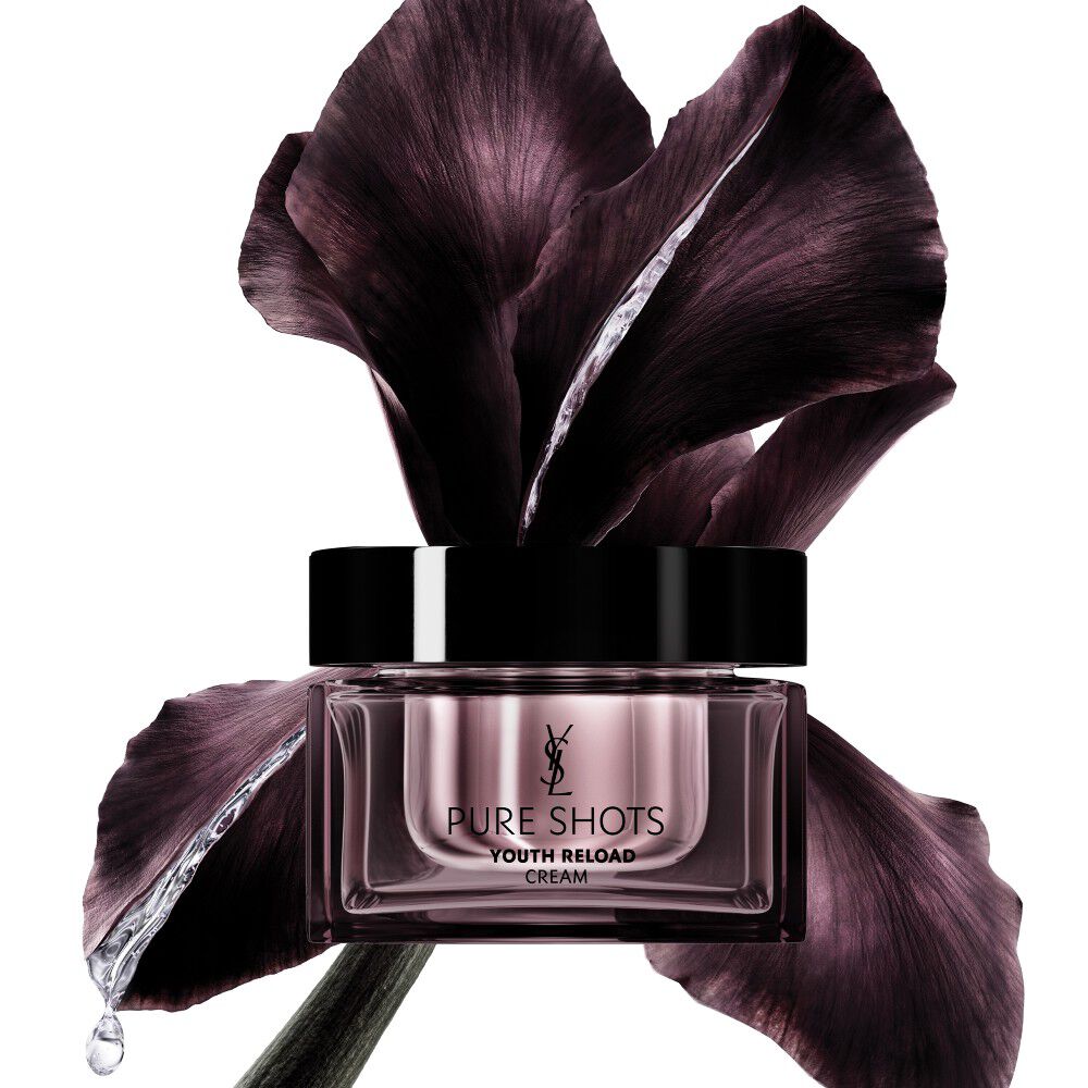 Pot de crème YSL Beauty Pure Shots Youth Reload, élégamment placé devant une fleur d'iris violette foncée.
