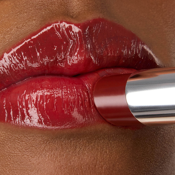 Gros plan du rouge à lèvres YSL LOVESHINE en teinte Berry Crush, nuance 219, appliqué sur les lèvres rouge vif, brillantes et lumineuses du mannequin Zahara.