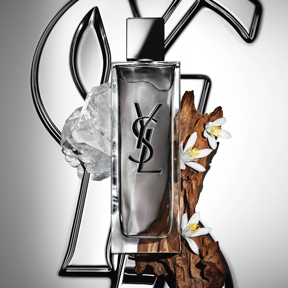 Le flacon de MYSLF Eau de Toilette Intense par YSL Beauty, entouré de fleur d’oranger, de bois et de muscs blancs.
