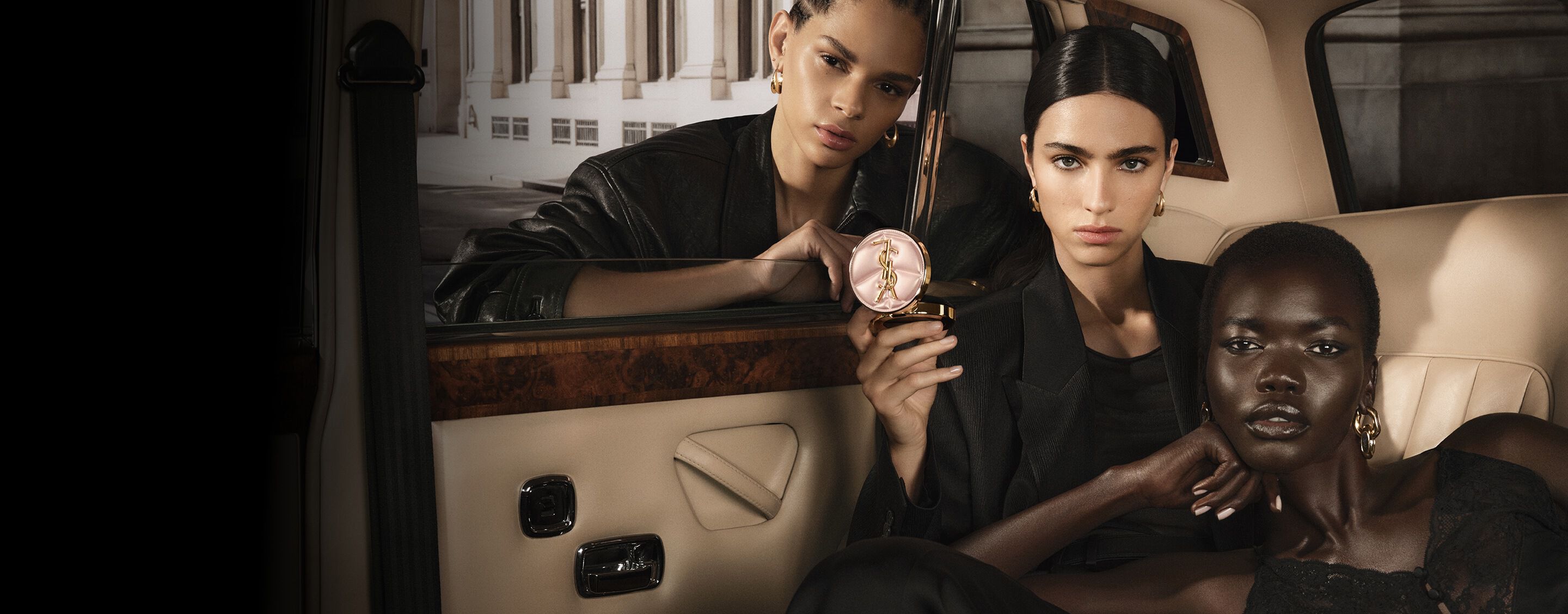 Trois mannequins dans un taxi avec YSL SKIN AFFAIR CUSHION. Teints variés et éclat haute couture.